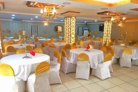 Merve Deluxe Düğün Salonu'nda yuvarlak masa ve altın rengi sandalye düzeni